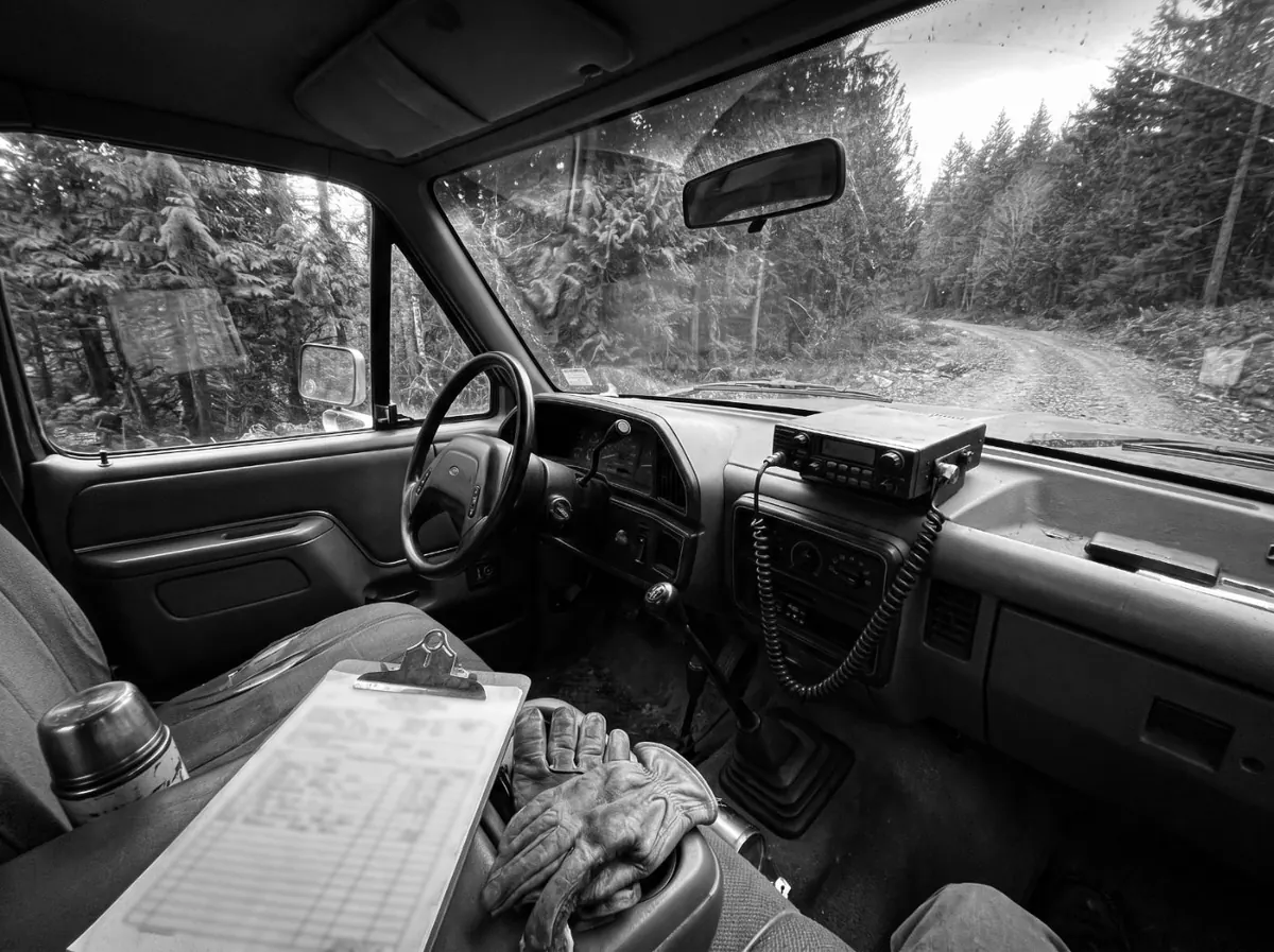 A work truck cab: a clipboard with a paper work order on the seat, a two-way radio on the dash